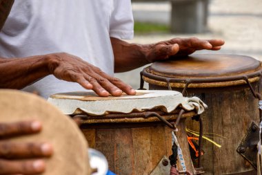Salvador, Bahia 'da Pelourinho sokaklarında afro-Brezilya Capoeira dövüş sunumu sırasında ilkel bir atabak çalan vurmalı çalgıcı
