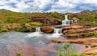 Diamantina, Minas Gerais, Brezilya 'daki Biribiri çevresel rezervinin kayalar ve yerel bitki örtüsü arasındaki berrak su şelalelerinin panoramik görüntüsü