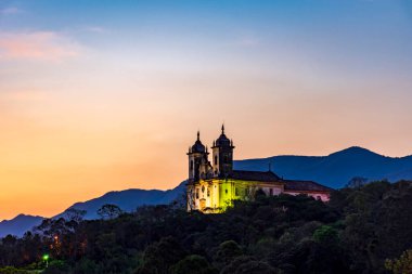 Gün batımında Minas Gerais 'deki Ouro Preto şehrindeki dağın tepesinde barok tarzında tarihi bir kilise.