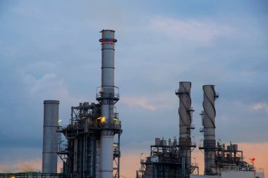 Petrol rafinerisi kimya fabrikası ve elektrik santrali. Gün batımında birçok depolama tankı ve boru hattı olacak..