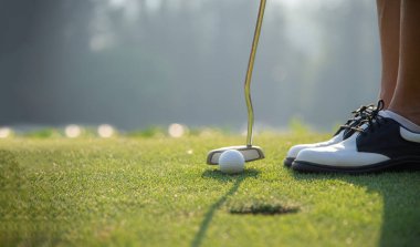 Golf oyuncusu yeşil gün batımında golf topuna vurdu. Sağlıklı ve Yaşam Tarzı Konsepti.