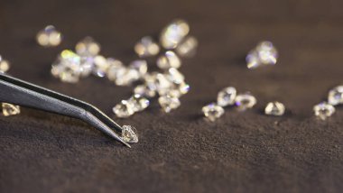 Cımbız ve büyüteçle elmas. Yere yansıyor. Cımbızla tutulan parlak kesilmiş elmas. Gemstone Güzelliği.