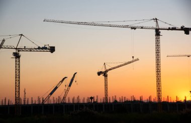 Endüstriyel vinçler ve güneş doğarken siluetler inşa etmek