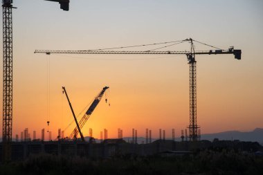 Endüstriyel vinçler ve güneş doğarken siluetler inşa etmek