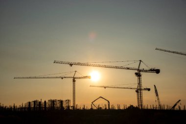 Endüstriyel vinçler ve güneş doğarken siluetler inşa etmek