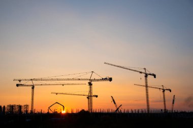 Endüstriyel vinçler ve güneş doğarken siluetler inşa etmek