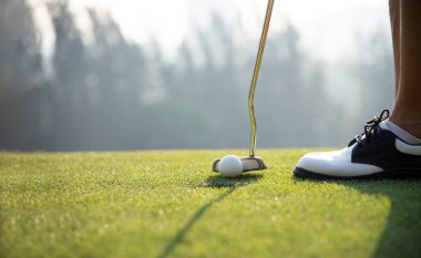 Yeşil çimlerde beyaz golf topu. Golf sopası ve yeşil sahada top. Spor, rahatlama, dinlenme gibi güneşli ışık golfçülerinde.