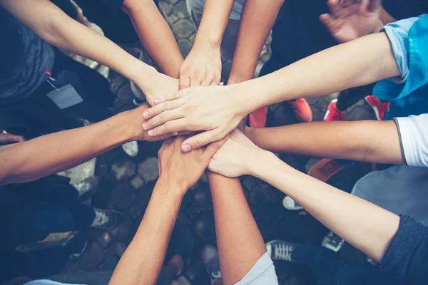 Young People Putting Their Hands Together On Top Of Each Other.Solidarity unite people hands together community teamwork.