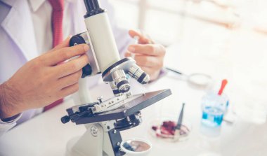 Bilim adamı laboratuardaki örnek bölmesine renkli sıvıyı döküyor.