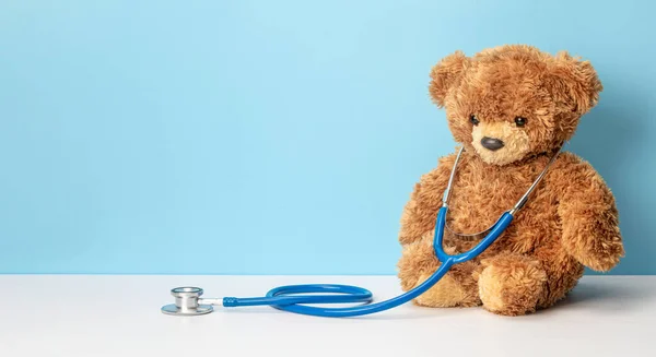 Mavi arka planda oyuncak ayı ve steteskop. Çocuk doktoru konsepti. Metin için şablon kopyalama alanı