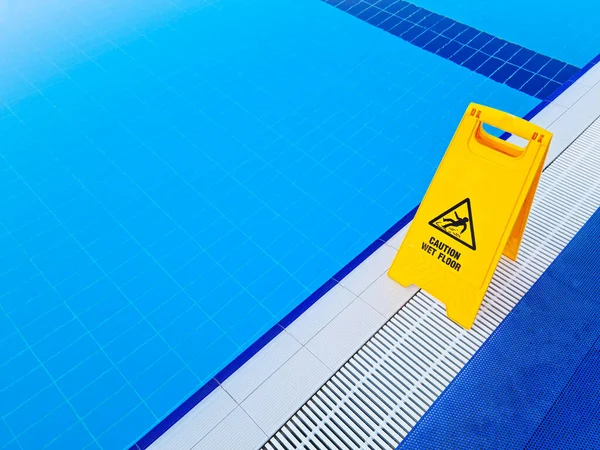 Caution Wet Floor. Yellow sign near the pool — Stock Photo, Image