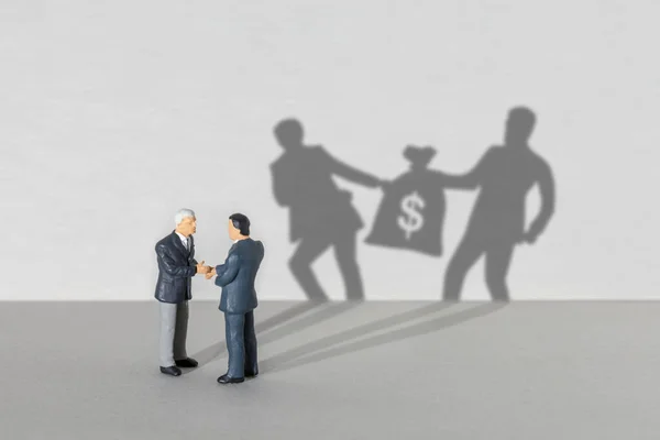 Profit sharing. Two businessmen in suits are shaking hands. SHADOW two businessmen take a bag of money from each other — Stock Photo, Image