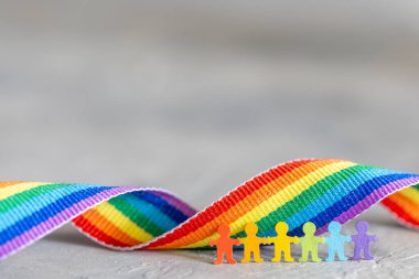 LGBT geçit töreni. Renkli adamlar gökkuşağı bayrağının önünde el ele tutuşuyorlar. Metin için şablon kopyalama alanı