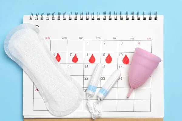 Menstruación. Forros panty con tampones y una copa menstrual en el fondo del calendario —  Fotos de Stock