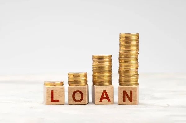 Rising stacks of coins and the word LOAN on a gray background — Stock Photo, Image