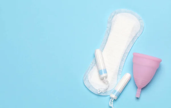 Menstruación. Higiene para la menstruación, almohadillas, tampones y un tazón para la menstruación sobre un fondo azul —  Fotos de Stock