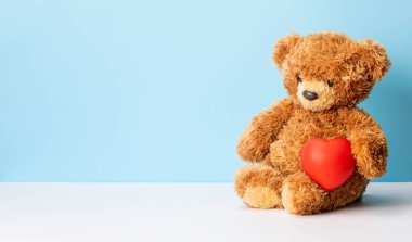 Oyuncak ayı arka planda bir kalp tutuyor. Sevgililer Günü