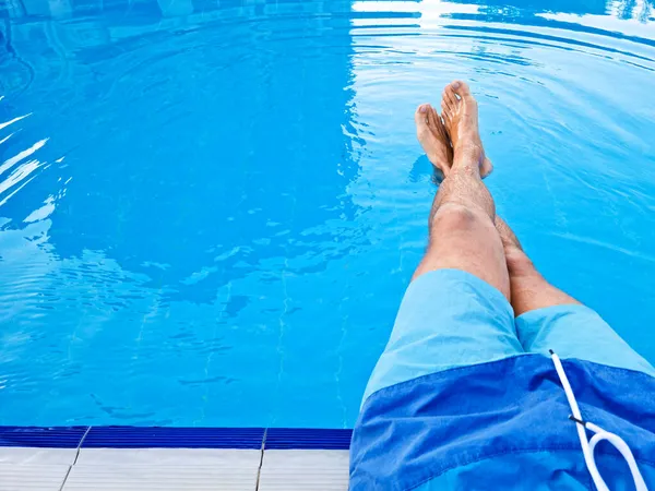 Jambes d'un homme dans la piscine. Relax concept. Modèle Copier l'espace pour le texte — Photo