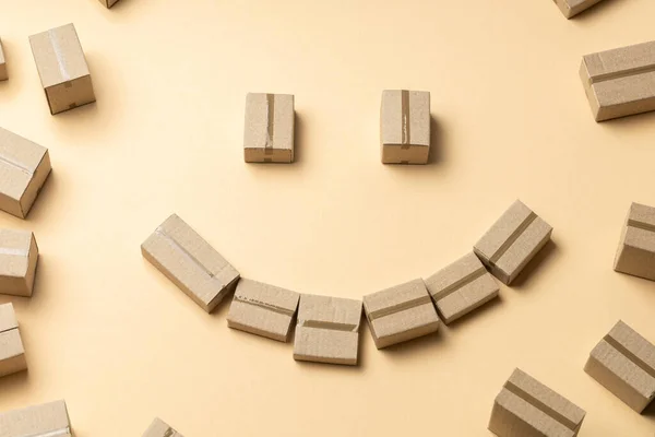 Rosto sorridente de caixas de papelão em um fundo marrom claro — Fotografia de Stock
