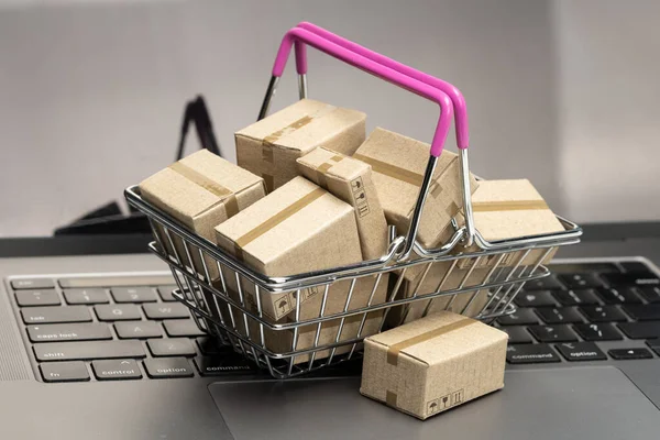 Online shopping. Laptop keyboard and shopping basket with cardboard boxes — Stock Photo, Image