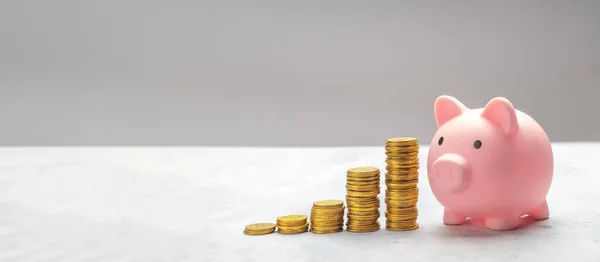 Hucha y pila de monedas de oro escalera sobre fondo gris. Plantilla Copiar espacio para texto. maqueta-up Imágenes de stock libres de derechos