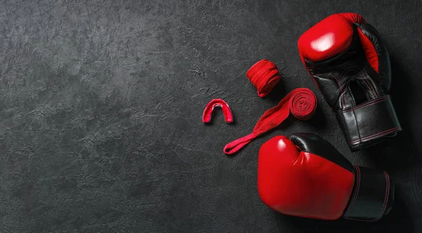 Guantes de boxeo rojos con protector bucal y vendajes de boxeo sobre fondo negro. Plantilla Copiar espacio para texto. maqueta-up Imagen De Stock