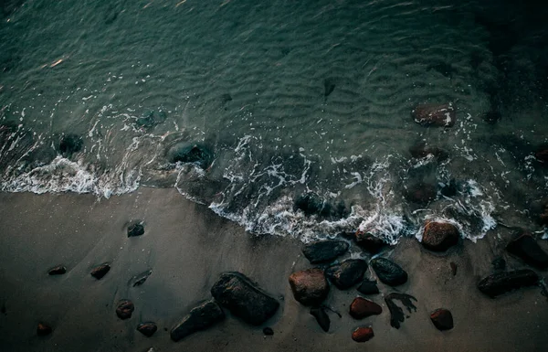 砂や石の海岸の海の波の泡の写真です — ストック写真