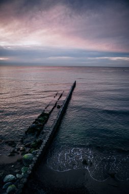 Baltık Denizi üzerinde gün batımı, dalgalı sular ve kayalarla dolu kıyılar