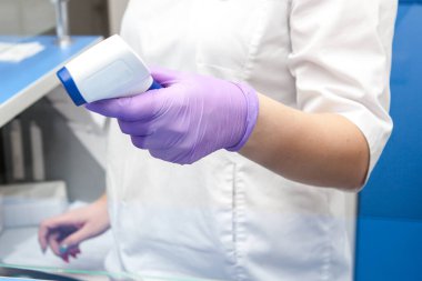 Doktor, elin sıcaklığını uzaktan ölçer.