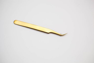 Kirpik uzatma ve kaş tasarımı için araçlar. Beyaz arka planda altın renkli kozmetik cımbızlar