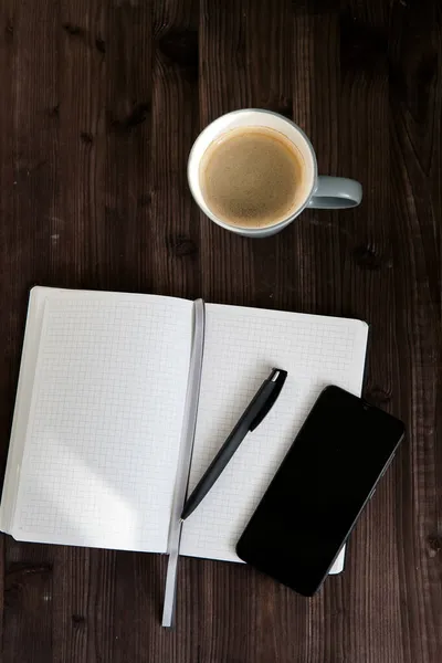 Ανοιχτό Λευκό Σημειωματάριο Μαύρο Κινητό Τηλέφωνο Και Ένα Φλιτζάνι Καφέ — Φωτογραφία Αρχείου