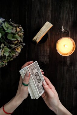  Tarot kartları ellerinde. Karanlık bir arka planda. Mum ışığında.