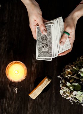  Tarot kartları ellerinde. Karanlık bir arka planda. Mum ışığında.