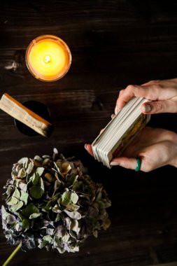 Tarot kartları ellerinde. Karanlık bir arka planda. Mum ışığında.