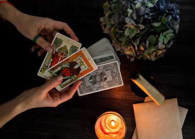  Tarot kartları ellerinde. Karanlık bir arka planda. Mum ışığında.