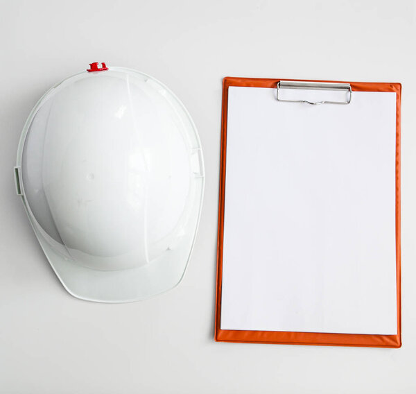 white constructionhelmet on a white background, notepad and pencil