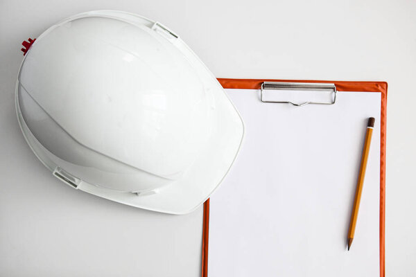 white constructionhelmet on a white background, notepad and pencil