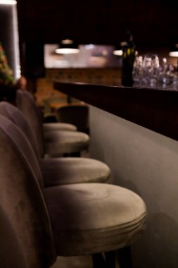 Bardaki yarı karanlık barda boş sandalyeler var. Gri bar tabureleri