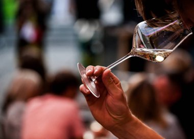 Kırmızı şarap kadehini tutan adamın eli. Kristal berrak şarap kadehinde şarapla el. Şarap barı ya da şaraphane. Ölçekleme.