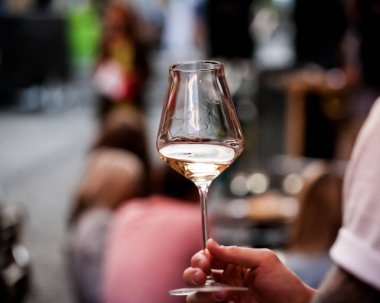 Kırmızı şarap kadehini tutan adamın eli. Kristal berrak şarap kadehinde şarapla el. Şarap barı ya da şaraphane. Ölçekleme.