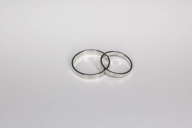 Beyaz arka planda beyaz metalden yapılmış klasik alyanslar.