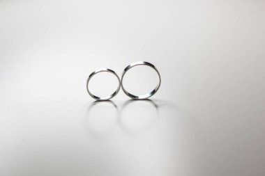 Beyaz arka planda beyaz metalden yapılmış klasik alyanslar.