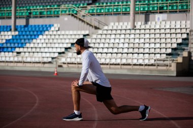 Spor stadyumu yeşili esneme, konsantrasyon öncesi ağrı eklemleri bağlar, vücut bacakları, beyaz yeşil.