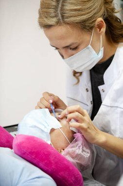 Bir kız, salgın sırasında kirpiklerini uzatma prosedürünü uygular. Elinde aletler olan bir usta.