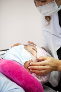 Bir kız, salgın sırasında kirpiklerini uzatma prosedürünü uygular. Elinde aletler olan bir usta.