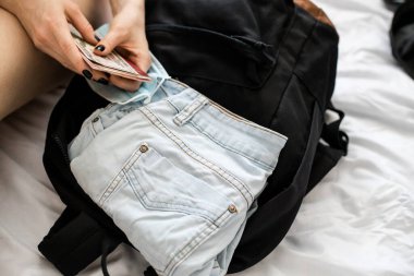 Kız siyah bir sırt çantasında elbise ve belgeler topluyor. Göç. Seyahate hazırlanmak, tatile çıkmak, mola, dinlenmek. İş gezisi.