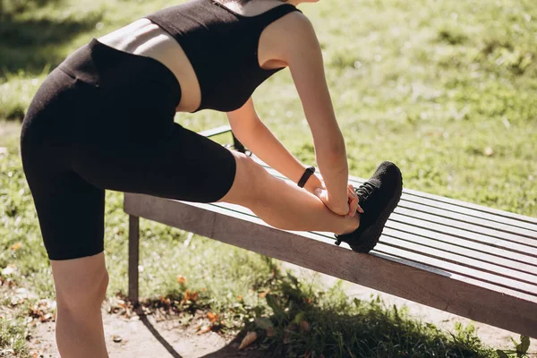 Portret van fitte sportieve jonge vrouw die zich uitstrekt in het stadspark. Outdoor training. Sport en een gezonde actieve levensstijl concept. Zwarte kleding voor sport — Stockfoto