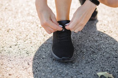 Spor ayakkabı bağcıklarını bağlayan kadın. Spor ayakkabılarını bağla. Spor ve sağlıklı aktif yaşam tarzı konsepti. Eğitimden önce spor ayakkabılarını bağlayan kız