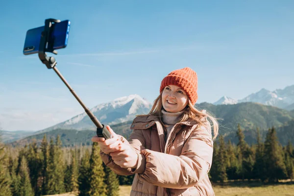 Junge Frau macht Selfie-Foto hoch oben in den Schneebergen und genießt die Aussicht. Freiheit, Glück, Reise- und Urlaubskonzept, Outdoor-Aktivitäten — Stockfoto