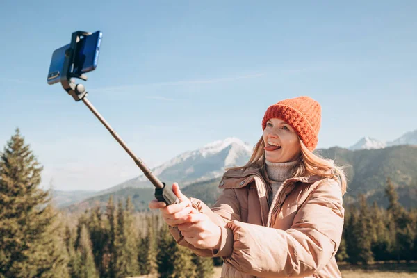 Junge Frau macht Selfie-Foto hoch oben in den Schneebergen und genießt die Aussicht. Freiheit, Glück, Reise- und Urlaubskonzept, Outdoor-Aktivitäten — Stockfoto